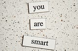3 blocks on a marble surface saying “you are smart”