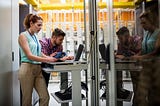 Two people working at a standing desk in an office setting.