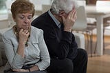 Two older people turning away from each other