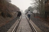 A couple balancing on railroad tracks