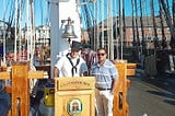 A man standing with a sailor on the deck of a ship.