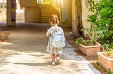 little girl walking into first day of kindergarten