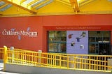 outside of Seattle Children’s Museum building with logo visible on red wall
