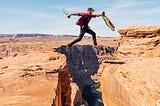 A man jumping above a cliff, symbolizing risk taking.