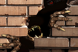 a monster with long claws and big teeth breaks through a brick wall. Red eyes are seen in the distance.