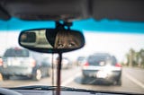 Woman looks at viewer through rear view mirror in car on crowded road