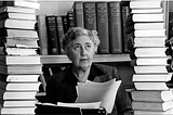 Agatha Christie with a stack of books over her table with her typewriter in the middle