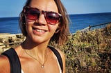 A photo of the author wearing sunglasses on a sunny day against the backdrop of a beach