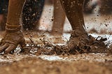 mutipe hands in muddy mess during ostacle course
