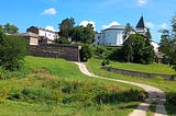A side view of the outside of the rounded church and stone tower of the Abbey of Gethsemani along with one of the paths leading to the abbey, outside of Louisville KY.