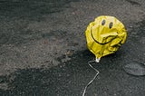 Deflated yellow balloon with smiley face