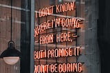 A window with a neon sign reading “i don’t know where I’m going from here but I promise it won’t be boring”