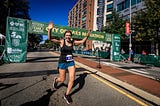 A female runner with arms raised celebrating at the finish line of a marathon