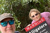 The writer and his daughter are standing by a sign warning of alligators