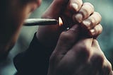 Young man lighting a marijuana joint