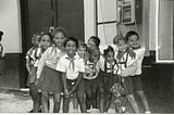 A group of young Cuban schoolchildren pose for a photo in the street