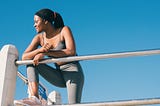 Young woman leaning over a rail outside and looking toward her right