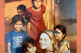 Young woman with blonde hair turns to look at the camera, smiling. She is surrounded by five other children of various ages, mugging for the camera