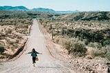 Woman walking on dirt road, arms outstretched