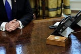 Resolute Desk in the Oval Office. In the center is a wooden box with a red button.