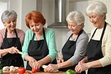 four older women cooking together in kitchen