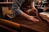 man working with leather textile at a workshop.