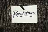 A paper with the word Resolutions, nailed onto a tree