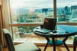 Computer at desk overlooking city views.