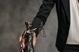 A man holding a small statue of “Justice of Peace” on the table.