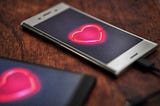 Two smartphones displaying bright red hearts.