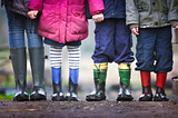 four children in boots and coats standing outside