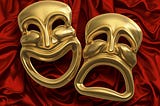 Classic comedy-tragedy theater masks against red curtain fabric.