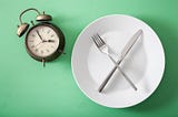 Clock with empty plate, knife and fork.
