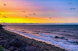 Sunset on a beach with gentle waves.