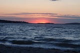 A vanishing pink-purple sunset over choppy bay water