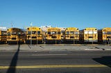 A photo of a bunch of buses parked in a lot.