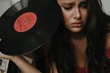 Woman holding vinyl record album, looking sad