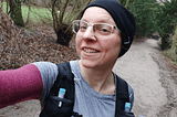 woman runner with black hat and white glasses smiling in the camera