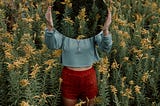 Image via Unsplash. Photograph of woman holding a mirror reflecting a field