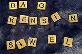 Beige game tiles with black lettering on a dark blue furry blanket display the name DAG … KENSIN… and SIWEL…