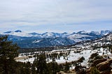 View of mountains and trees with a snow-covered foreground.