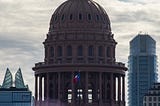 A telephoto picture of the top of the Texas State Capitol in Austin, Texas. The skyline looming in the background.