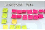 Improvement ideas written on sticky notes are listed on a white dashboard