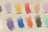 Swatches of twelve watercolor paints on parchment paper