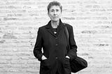Blanco y negro. Mirando a cámara, Silvia Federici en un saco negro, con su clásico pelo corto. Detrás una pared de ladrillos