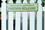 White picket fence with a “Friends Welcome” sign on it