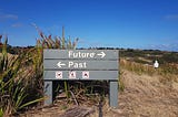 A wayfinding sign of the side of an Australian hiking trail, that reads ‘Future’ with an arrow pointing to the right, and underneath it, ‘Past’ with an arrow pointing to the left.