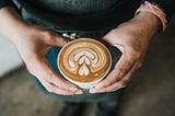 Close up of hands holding a cup of coffee with a heart