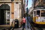 A lady wearing a sergical mask walks the empty streets of Lisbon.