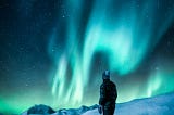 Man standing near snow field and admiring the northern lights